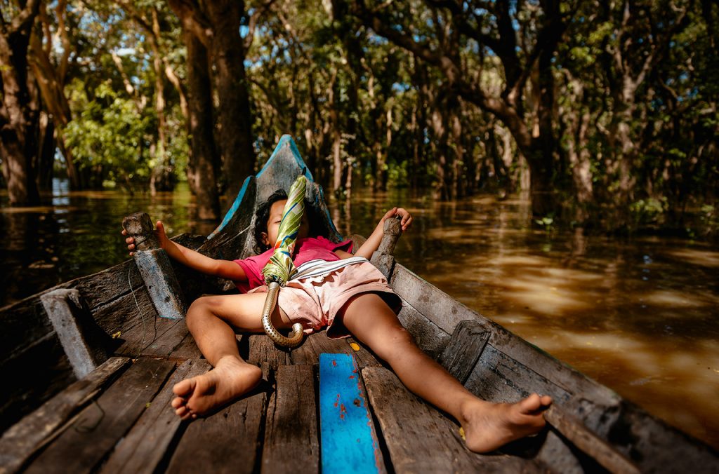 Sleeping girl on boat in flooded forest